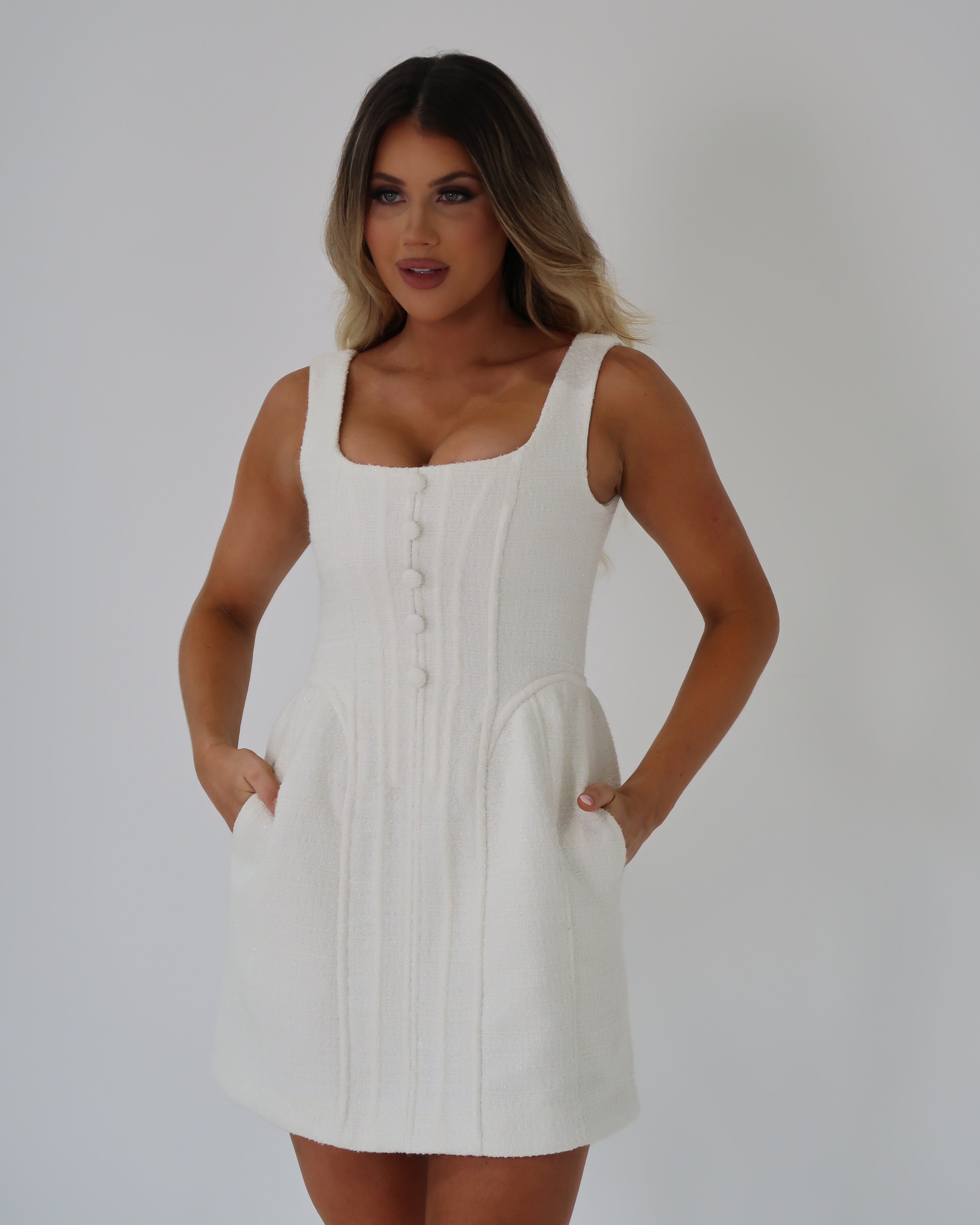 White boucle mini dress with a square neckline, thick straps and button detailing in the same fabric. This dress also boasts functional hidden pockets by Jador the label