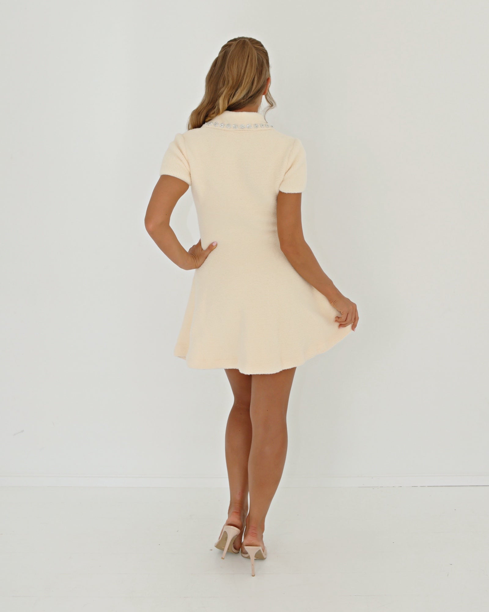 Woman wearing a cream-colored dress against a white background

